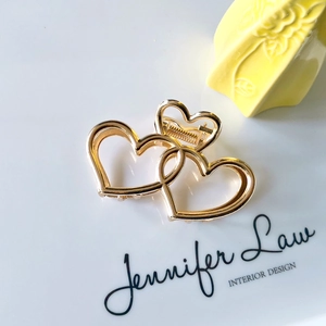 Polished gold metal hair claw clip featuring a hollow triple heart design on white card