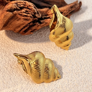 Golden seashell stud earrings in S925 silver on white sand and driftwood background