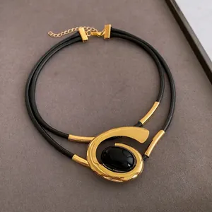 Double-layered black cord necklace with oval black stone and gold spiral metal pendant