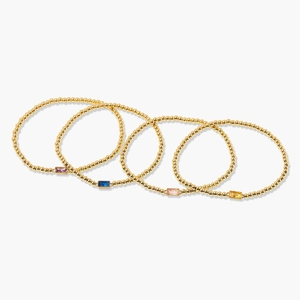 Detail of five gold bead bracelets featuring colorful rectangular birthstone crystals