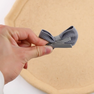 Close-up of grey fabric bow hair clip featuring a ribbon-wrapped alligator metal clip