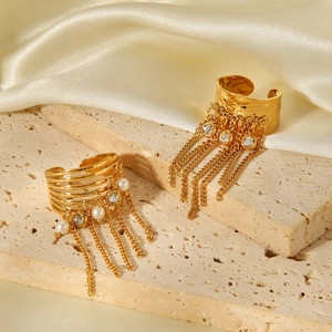 Detail of gold tassel open ring with pearls and crystals on beige stone props