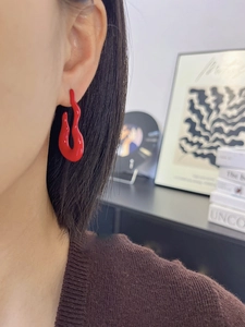 Close-up of modern vibrant red streamlined abstract earrings on a model person