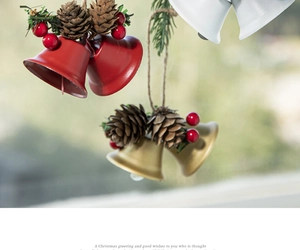 Close-up of Christmas ornaments featuring red and gold metal bells with pine cones and berries
