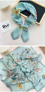 Detail of mint green silk scarf with floral pattern and premium satin texture