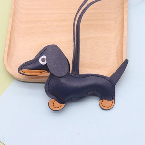 Detail of leather dachshund bag charm with litchi texture on a wooden tray