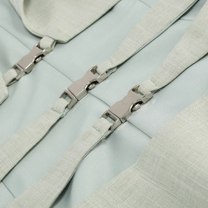 Détail de boucles en métal argenté et sangle vert menthe sur une robe à col en V