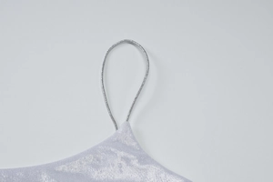 Dettaglio del tessuto metallizzato argento glitterato e della sottile spallina di un abito