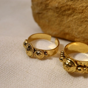 Vintage gold adjustable rings with lion head relief and bead details on textured fabric