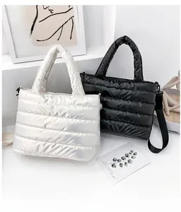 Close-up of quilted puffer tote bags in silver and black on a minimalist white pedestal
