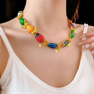 Primo piano di una collana vintage dorata con ciondoli in smalto colorato e fiocchi