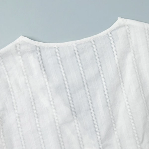 Detailed close-up of white blouse neckline featuring vertical textured stripe fabric