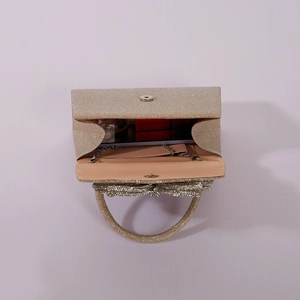 Internal view of gold rhinestone evening clutch bag with bow showing phone and lipstick