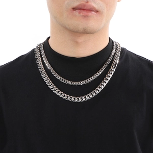 Close-up of a man wearing two silver polished Cuban link chains in different lengths