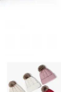 Detail of cable knit beanies with faux fur pom-poms showing ribbed cuff and thick texture
