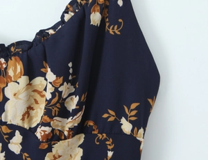 Detail of floral printed dress featuring ruffled neckline and navy blue chiffon texture