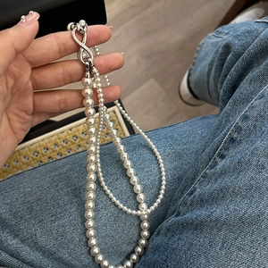 Detail of double-layer pearl necklace featuring a zircon infinity clasp and white beads