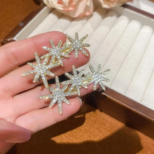 Detailed close-up of sparkling starburst hair clips with crystals on a golden base