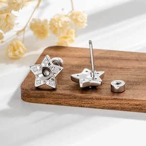 Minimalist silver star earrings with sparkling rhinestones on dark wooden base background
