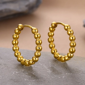 Detailed view of 18k gold plated beaded hoop earrings on a grey stone base