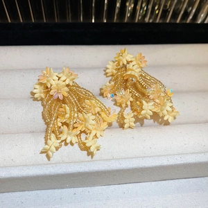 Detailed view of yellow flower tassel earrings with resin petals and bead strings