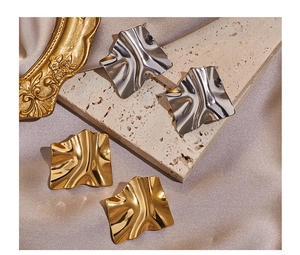Dettaglio degli orecchini quadrati testurizzati in oro e argento su display di lusso