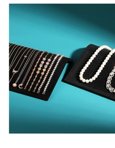 Close-up of various gold necklaces and pearl bracelets on black velvet jewelry stands