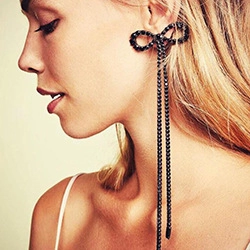 Close-up of elegant long black bow earrings with sparkling tassel beads on a model