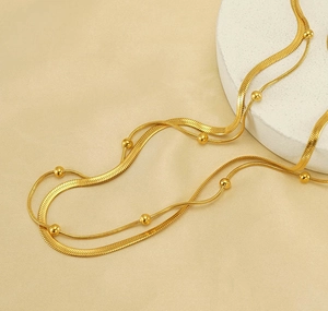 Detailansicht der goldfarbenen Edelstahl-Doppelschicht-Schlangenkette und Perlenhalskette