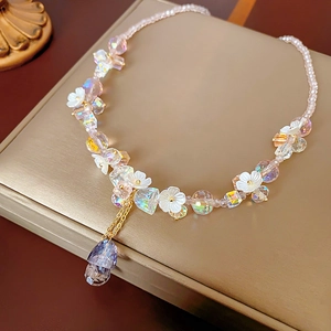 Detail of beaded flower necklace with crystal pendant and gold tassels on a gift box