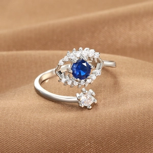 Silver adjustable Evil Eye ring with blue and white crystals on textured brown fabric