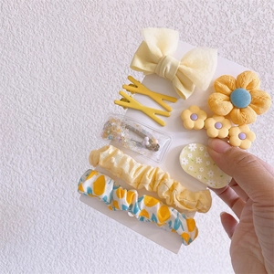 Detail view of yellow floral hair clips and scrunchies set on white display card