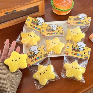 Detail of yellow plush star charms with colorful packaging cards on a wooden table