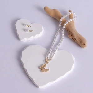 Minimalist pearl necklace with butterfly pendant and earrings on white heart stands