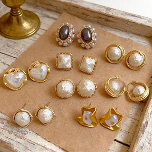 French vintage gold earrings set featuring pearls and gemstones on wooden tray