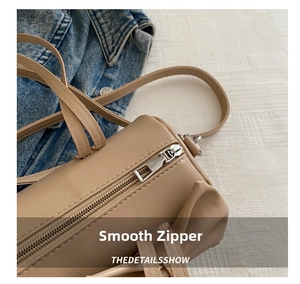Macro view of smooth metal zipper detail on a khaki leather underarm pillow bag