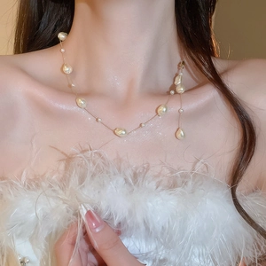 Detail of baroque pearl Y-necklace with champagne gold beads on model collarbone