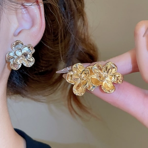 Detailed view of polished golden metal flower earrings featuring a 3D floral petal design
