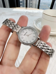 Close-up of silver steel strap watch with diamond bezel and white Arabic dial