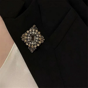 Close-up of vintage baroque brooch with crystals and pearls on a black blazer lapel