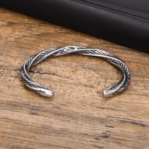Close-up of vintage silver cuff bracelet featuring detailed feather texture and twisted design