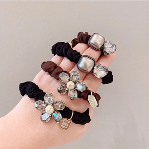 Elastic floral crystal hair scrunchies in black and brown colors worn by a model