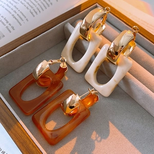 Detail of geometric rectangle earrings in amber brown and creamy white resin textures