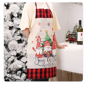 Close-up of beige Christmas apron with gnomes, red plaid trim and Joy to the world text