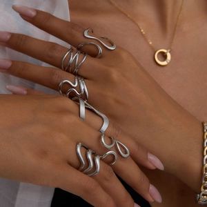 Close-up of wavy minimalist stainless steel rings set on a model's hand with silver finish