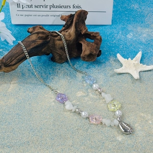Close-up of colorful floral beads and silver shell pendant on a beach-themed necklace