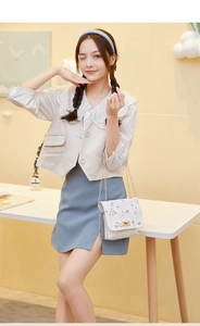 Detail of white small square bag with floral embroidery and chain strap on a model