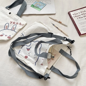 Detail of white canvas tote and crossbody bag featuring cute cartoon animal prints