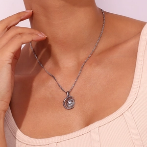Close-up of a silver crescent moon and eye pendant necklace with a zircon on a model