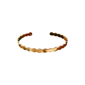 Minimalist twisted geometric open gold bangle with wave-edged glossy finish
